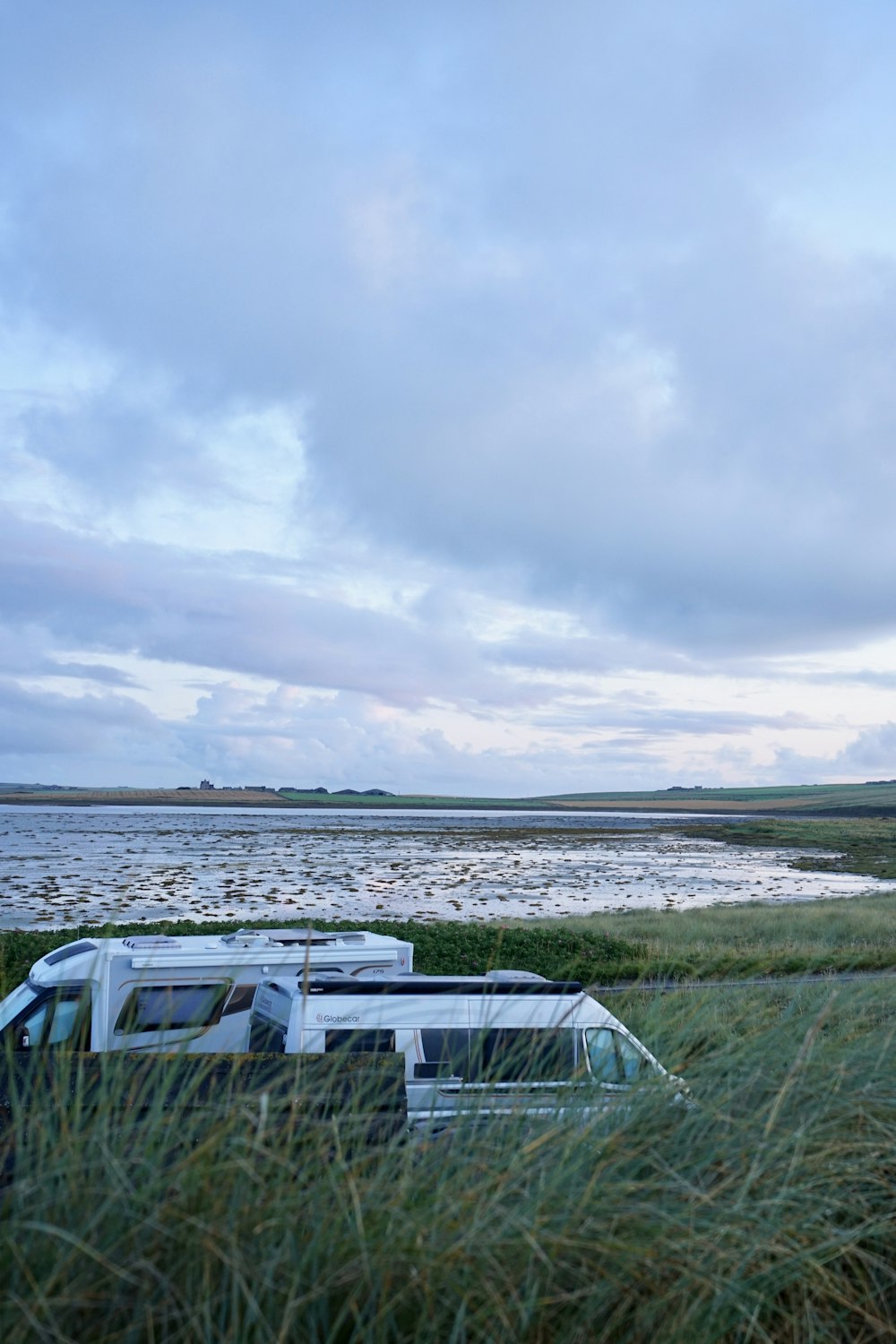 a bus is parked in the grass by the water