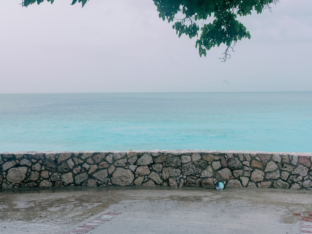 a stone wall next to a body of water