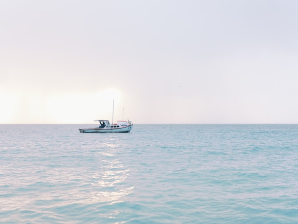Soft morning light over a calm sea with a small sailing boat on the horizon