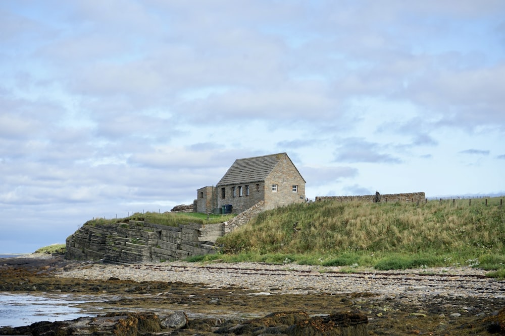 a house sitting on top of a hill next to a body of water