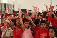 A group of kids proudly holding up their handmade paper crafts, smiling wide.