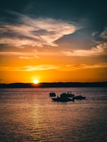 A stunning sunset over the Tanguar Haor wetlands with boats in the foreground.