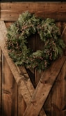 Colorful wreaths and garlands hanging on a rustic wooden door.