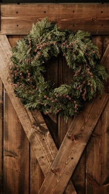 Colorful wreaths and garlands hanging on a rustic wooden door.