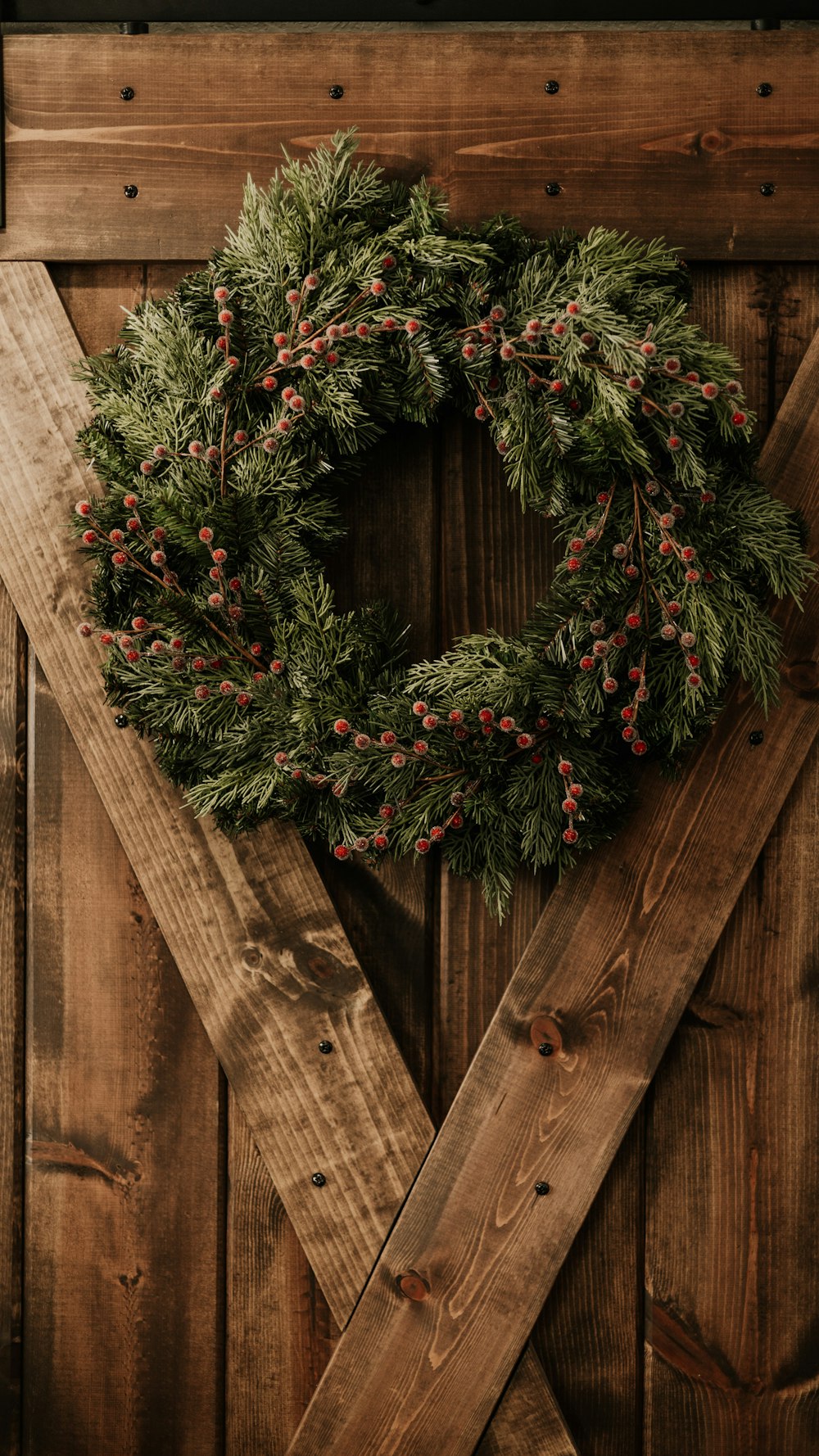 a wreath on a wooden door with red berries