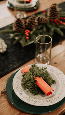 A set of embroidered napkins featuring floral designs and initials, arranged around a festive holiday table setting.