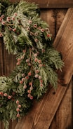 A festive wreath made from natural, recycled materials with vibrant red and green accents.