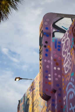 A vibrant street mural blending retro psychedelic patterns with urban cityscape elements under a sunset sky.