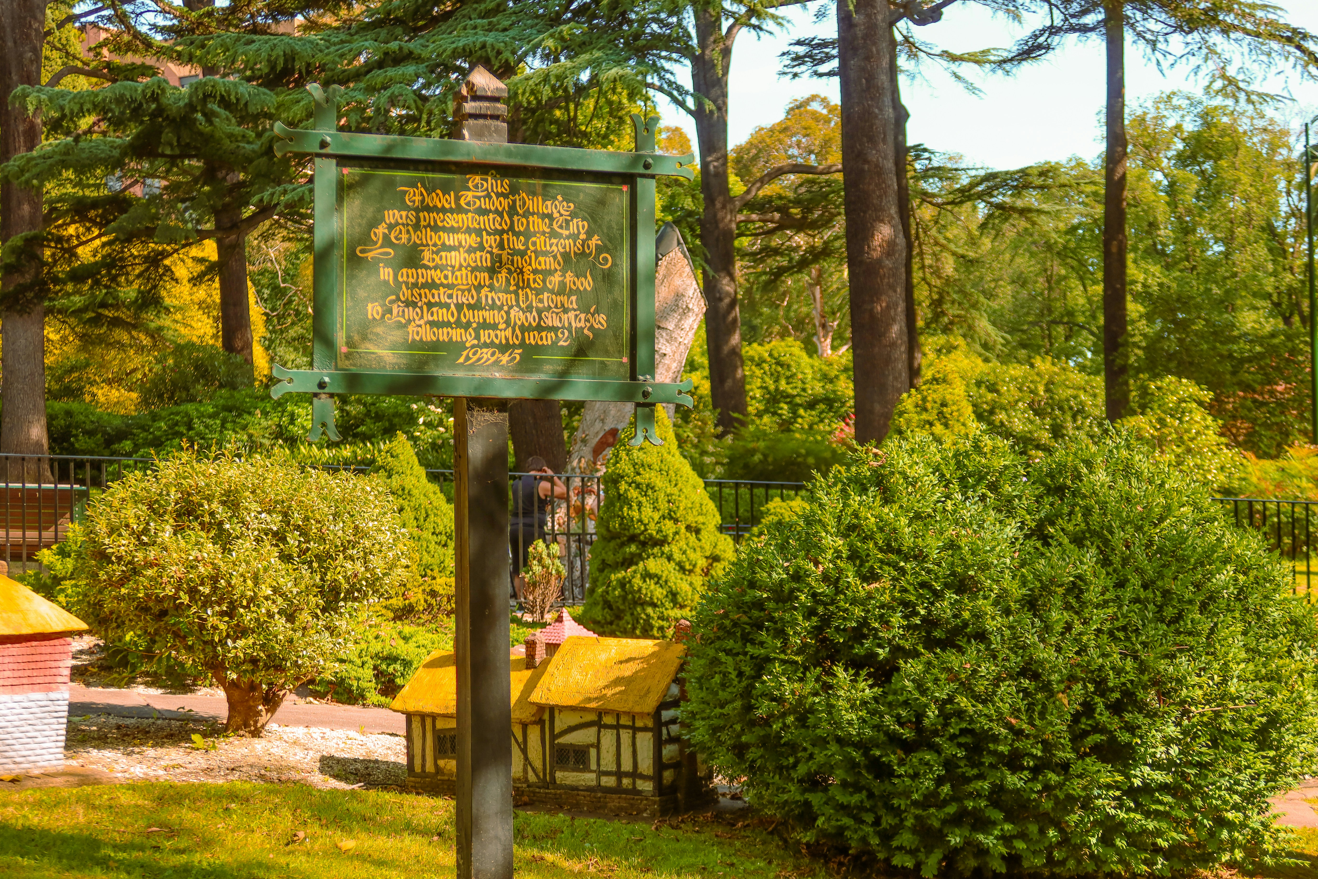 Heritage sign among rounded shrubs and tall trees in a garden