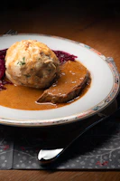 A hearty plate of homemade Austrian dumplings with rich sauce and fresh herbs.