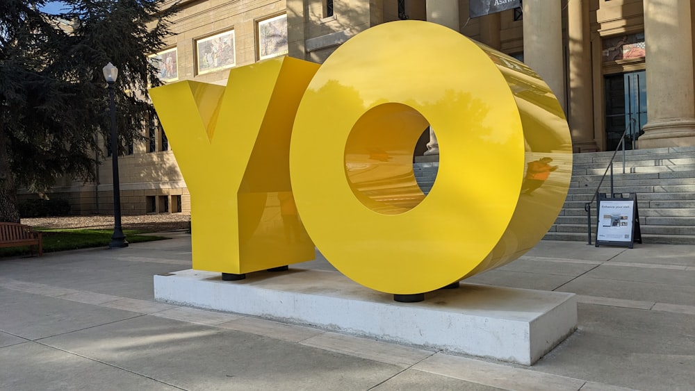 um grande objeto amarelo sentado em frente a um edifício