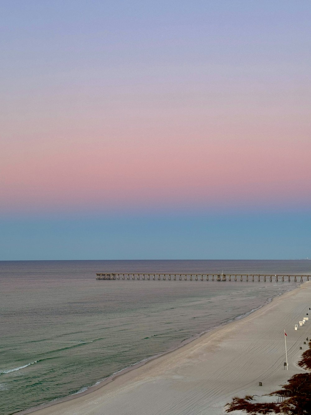 a view of a beach with a pier in the distance