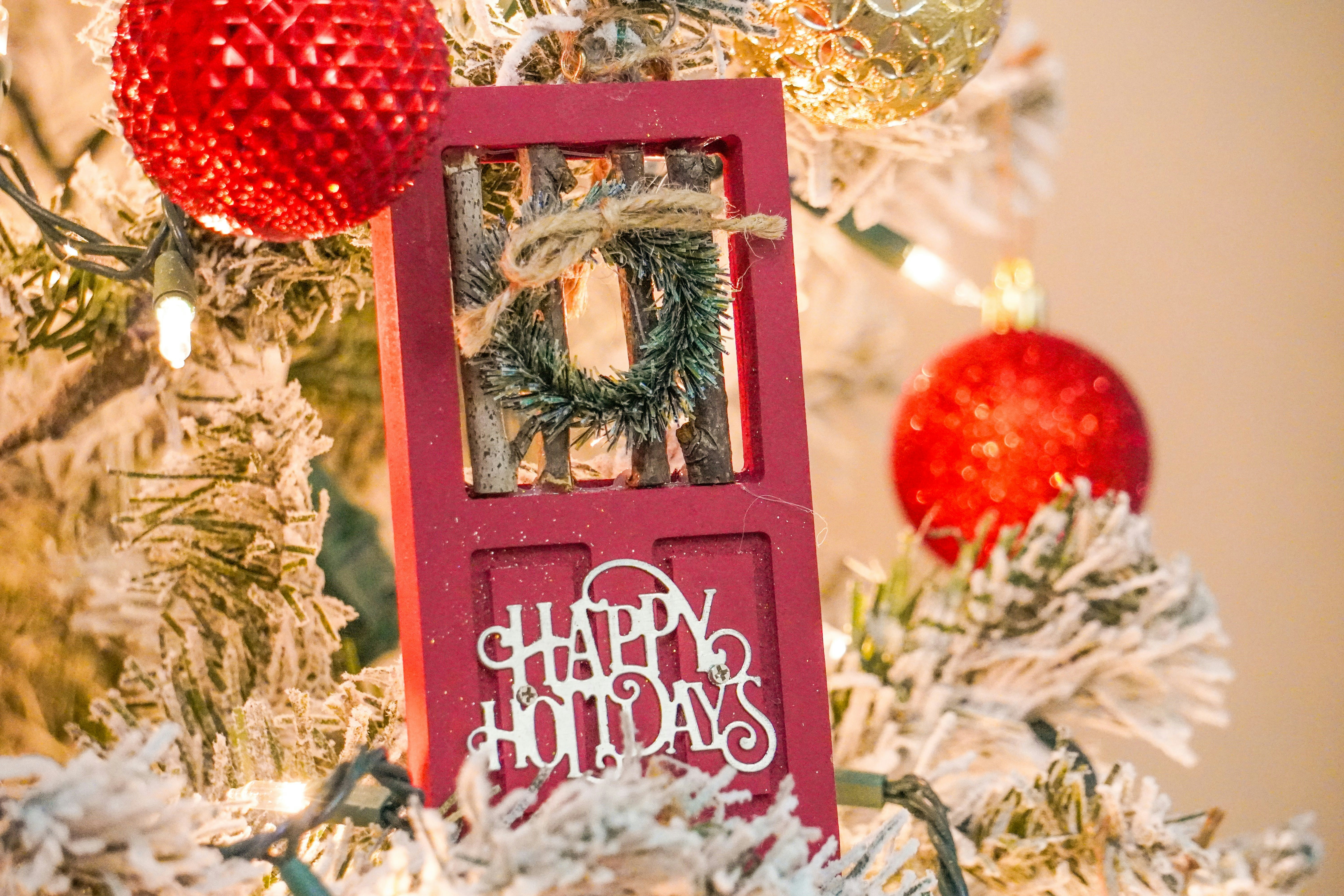 a christmas tree with ornaments and a red door
