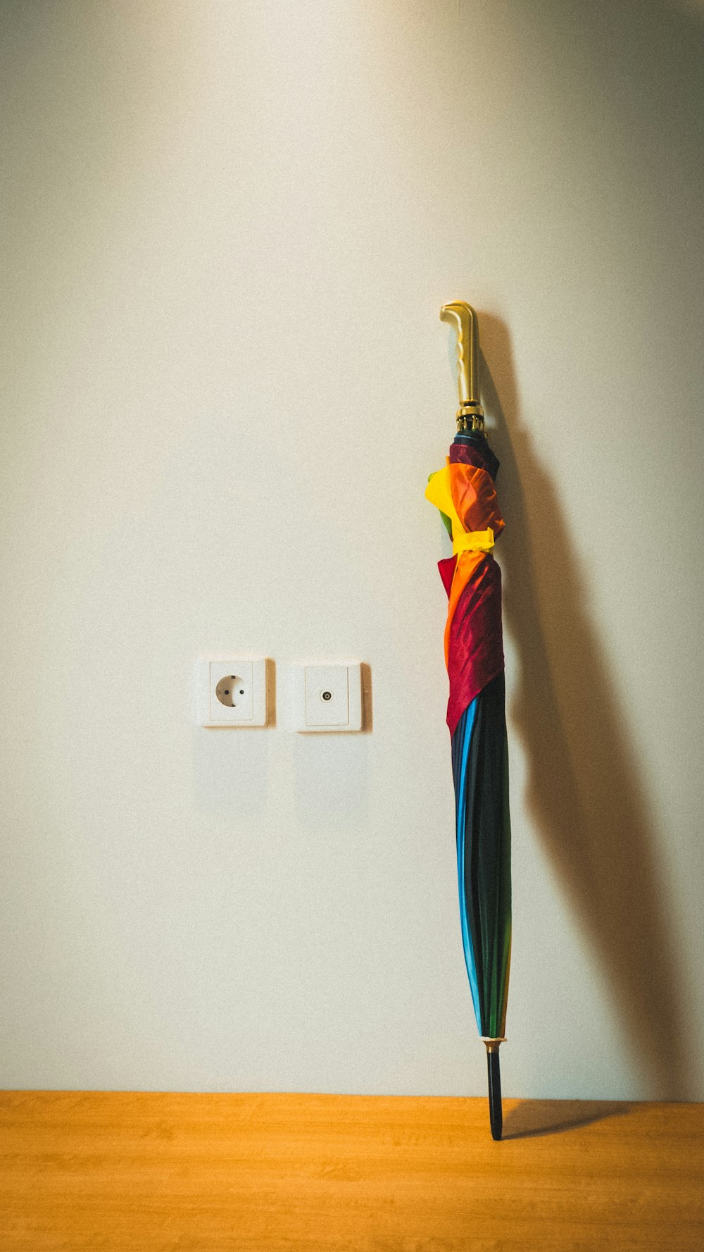 a colorful umbrella hanging from a wall next to a light switch