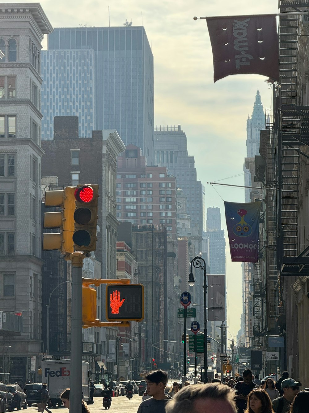 a group of people walking down a street next to tall buildings