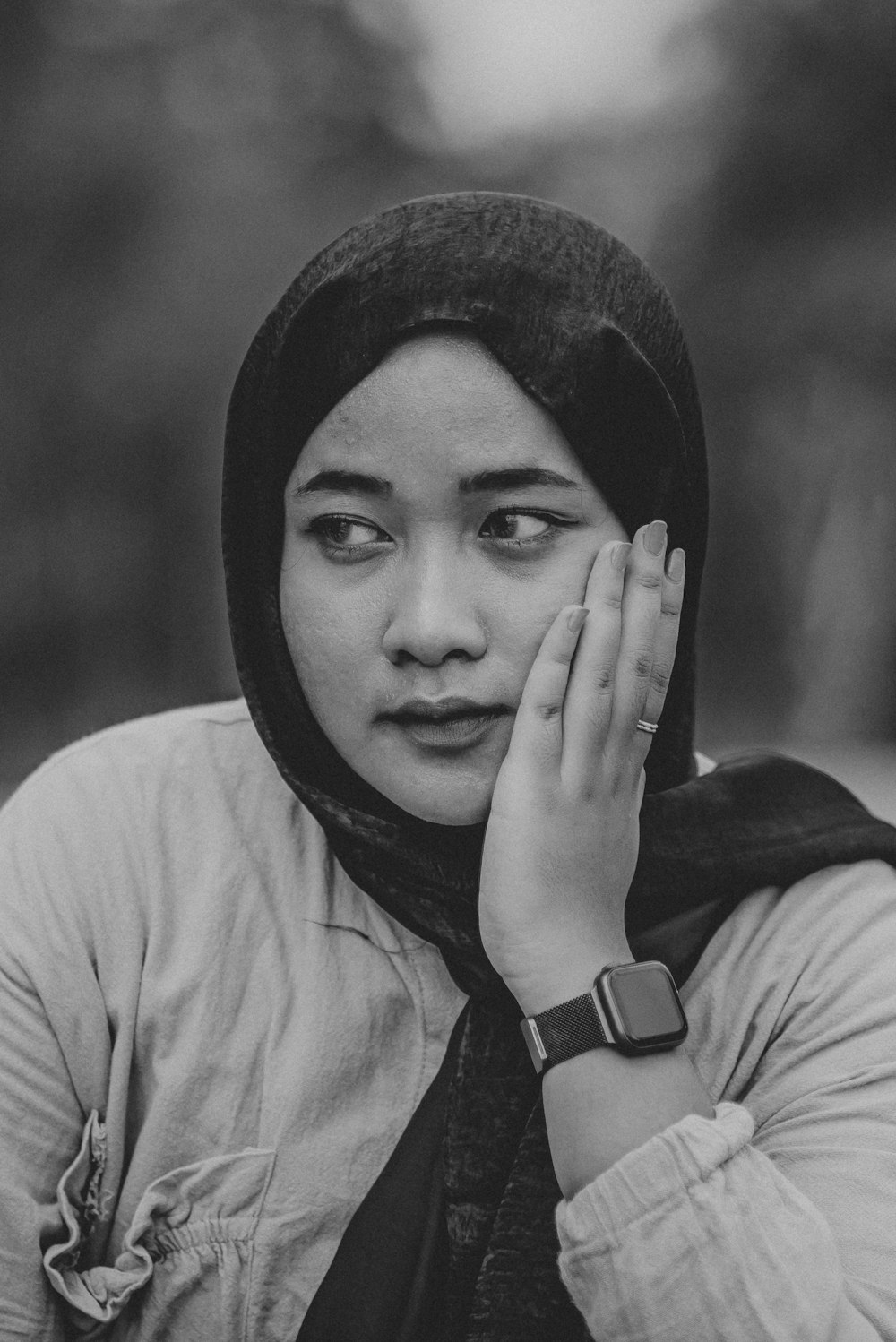 a woman in a headscarf covers her face with her hands