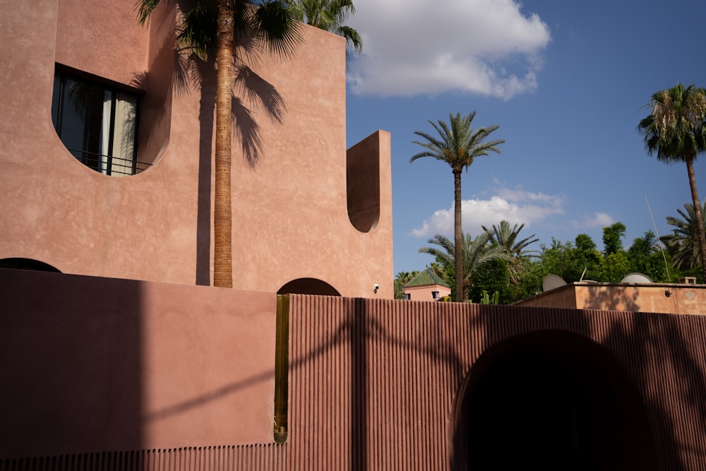 a pink building with a palm tree in front of it