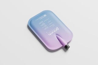 A sleek, modern water pouch features a gradient color scheme from blue to purple with white text labeling its specifications and brand name. The design is minimalist with a clean surface and a black spout.