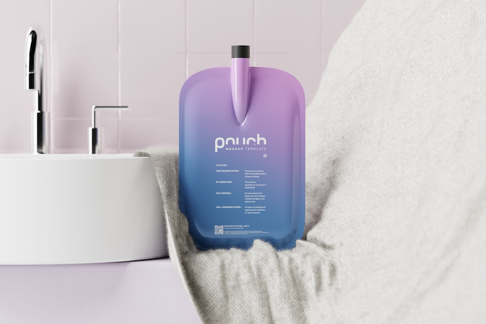 a purple bottle sitting on top of a bed next to a sink