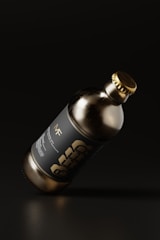 A dark glass bottle with a metallic cap is tilted against a dark background. The label on the bottle features bold typography with the word 'BEER'. The overall aesthetics of the image suggest minimalistic and modern design with an emphasis on sleekness.