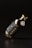 A dark glass bottle with a metallic cap is tilted against a dark background. The label on the bottle features bold typography with the word 'BEER'. The overall aesthetics of the image suggest minimalistic and modern design with an emphasis on sleekness.