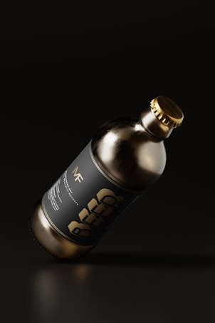 A dark glass bottle with a metallic cap is tilted against a dark background. The label on the bottle features bold typography with the word 'BEER'. The overall aesthetics of the image suggest minimalistic and modern design with an emphasis on sleekness.
