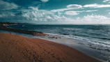 A serene beach at dawn with soft waves and footprints in the sand.