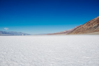 A breathtaking panoramic view of the vast white salt flats under a clear blue sky.