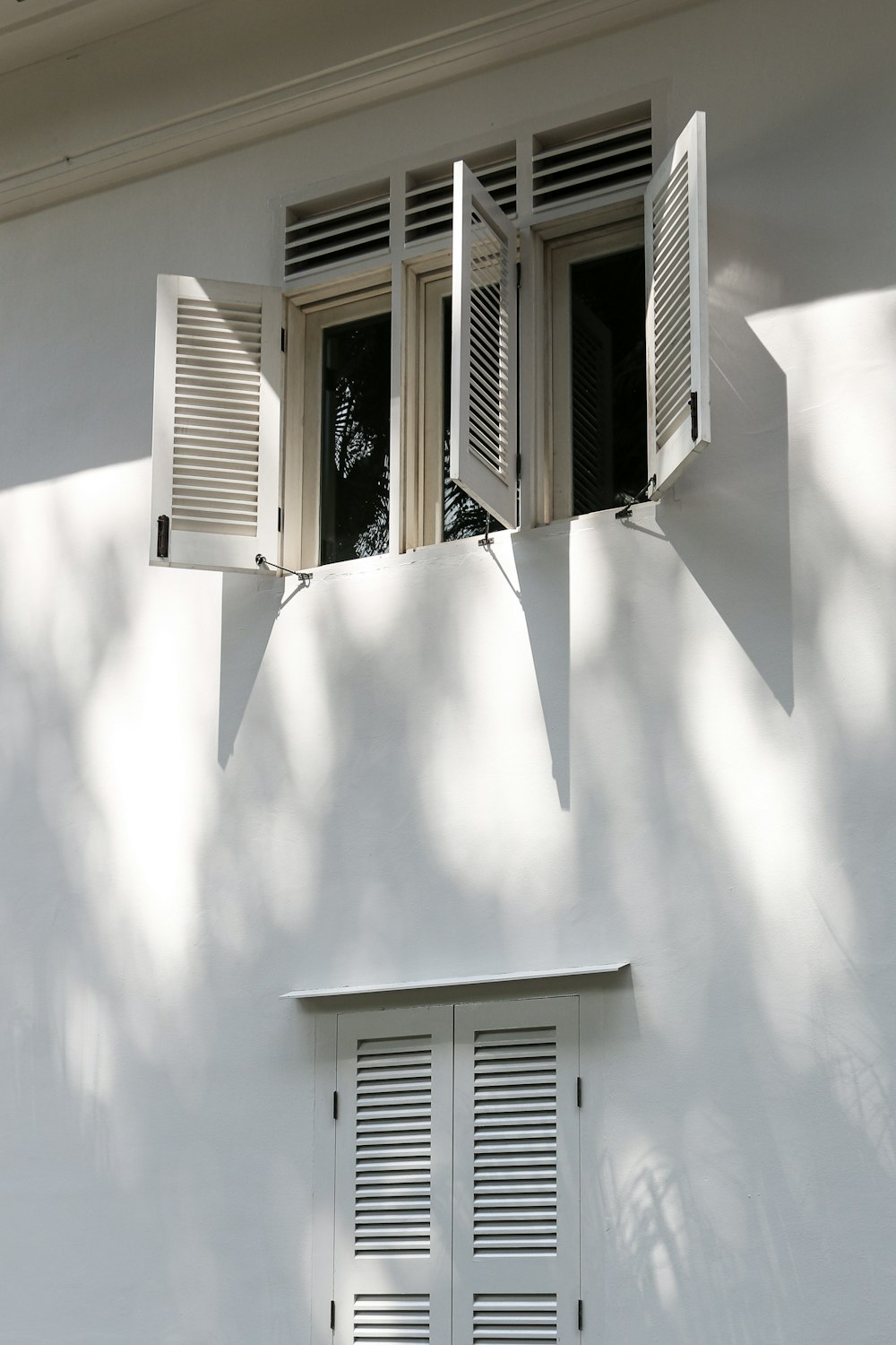 a white building with two windows and shutters
