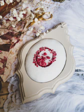 Close-up of an elegant embroidered wedding hoop with floral patterns and names stitched in soft colors.