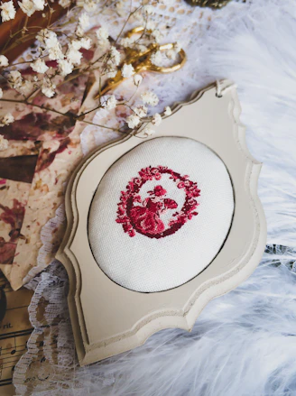 Close-up of a delicate pink embroidery hoop with intricate floral patterns on soft fabric.