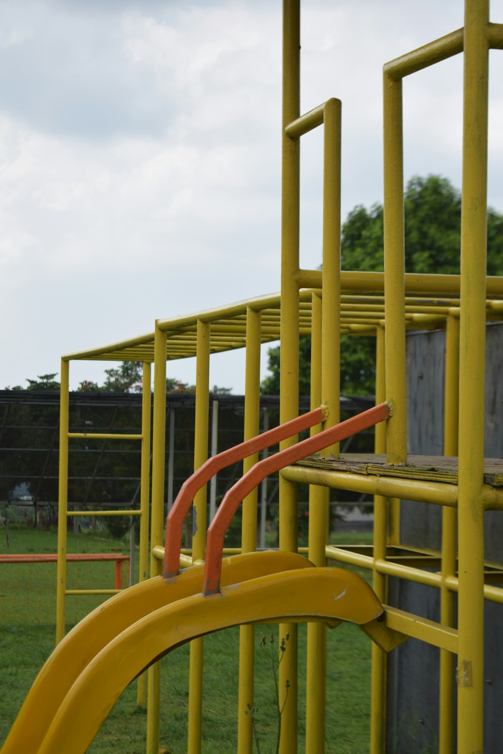 a yellow playground structure with a red slide