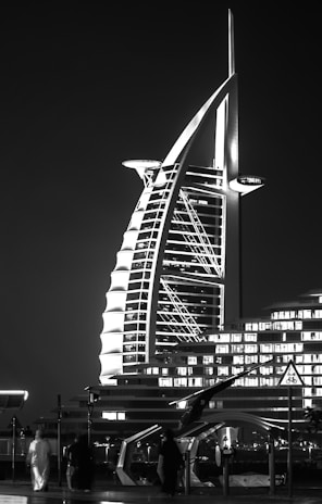 The iconic sail-shaped Burj Al Arab glowing golden under the evening sky with reflections shimmering on the water.