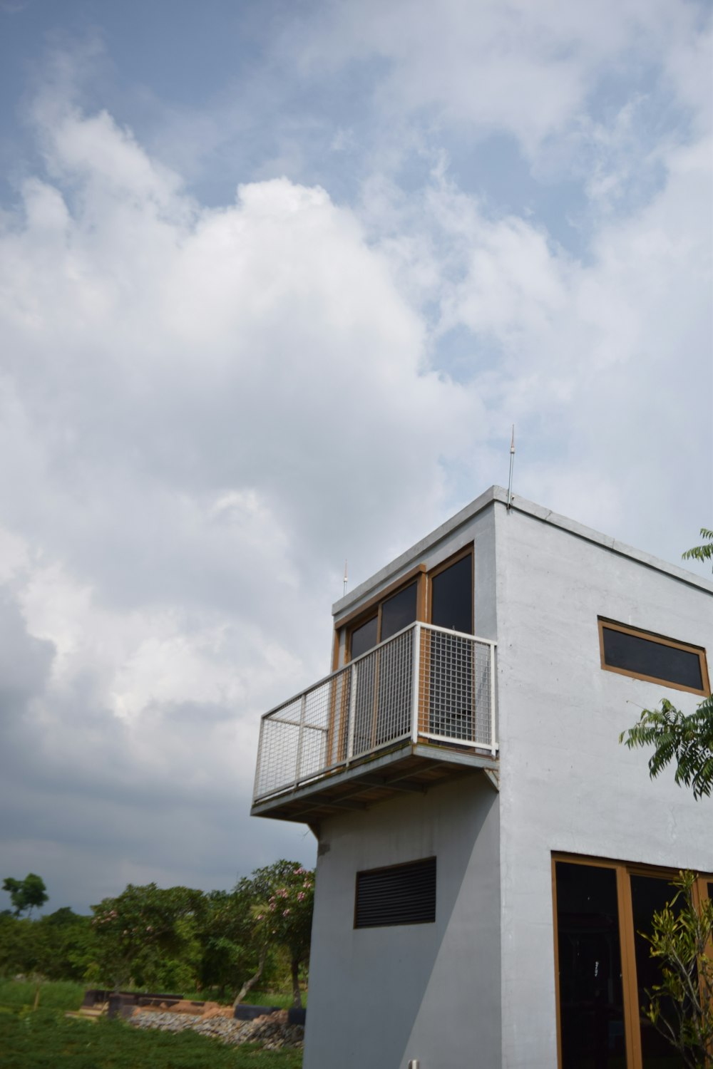 a white house with a balcony and a tree