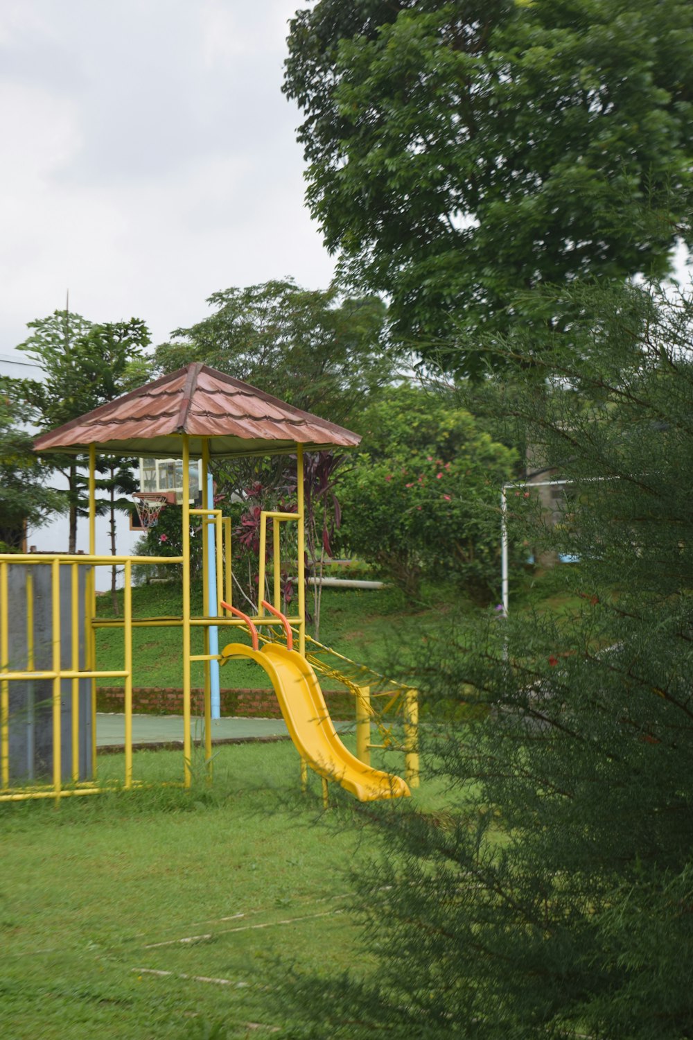 a playground with a yellow slide in the grass