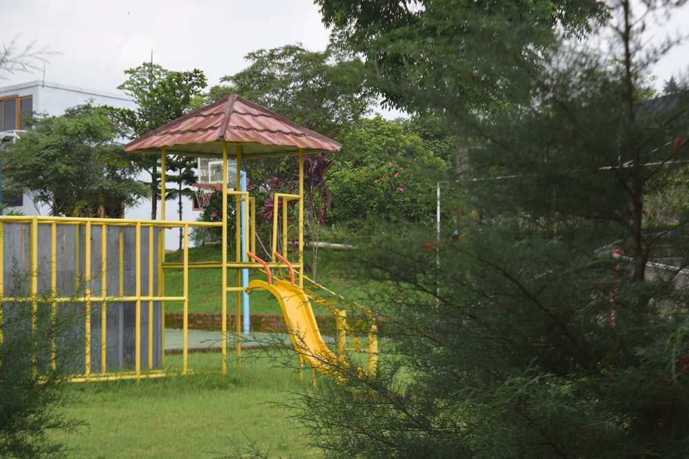 a yellow slide in the middle of a park