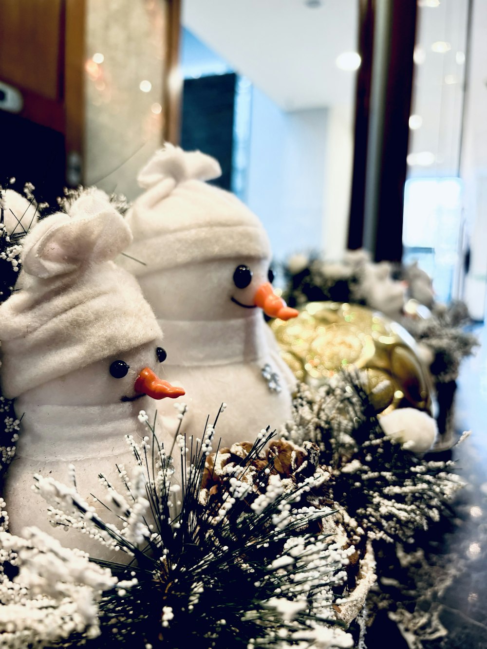 un couple de bonhommes de neige assis au sommet d’un arbre de Noël