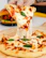 Close-up of a cheesy, freshly baked pizza slice being lifted from a wooden board.