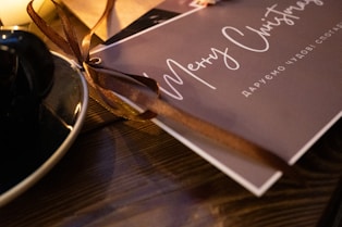 Close-up of a beautifully designed holiday tumbler with snowflakes and a personalized message, resting on a wooden table.