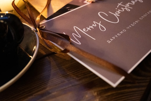 Close-up of a beautifully designed holiday tumbler with snowflakes and a personalized message, resting on a wooden table.