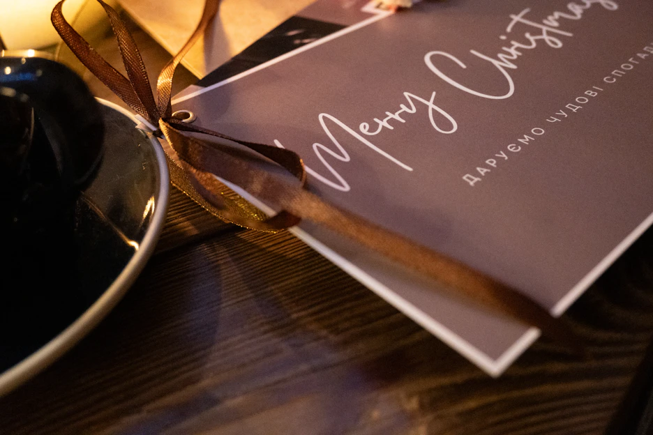 A close-up of luxurious gold-stamped Christmas cards, elegantly arranged on a festive wooden table.