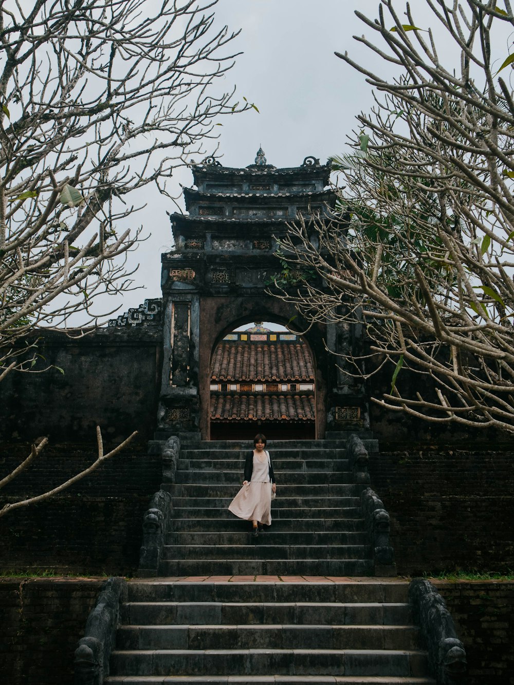 a woman in a white dress standing on a set of stairs