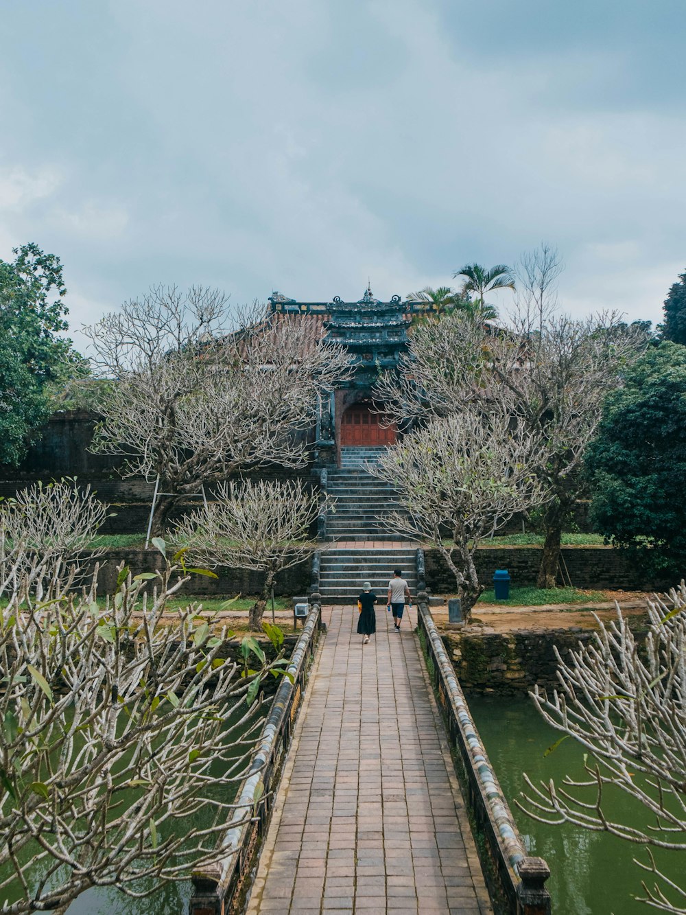 a brick walkway leading to a pagoda in a park