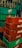 Stacks of green and red plastic crates, with empty glass bottles. The crates are branded with Pepsi and Coca-Cola logos. The bottles are clear and placed in a disorganized manner.