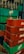 Stacks of green and red plastic crates, with empty glass bottles. The crates are branded with Pepsi and Coca-Cola logos. The bottles are clear and placed in a disorganized manner.