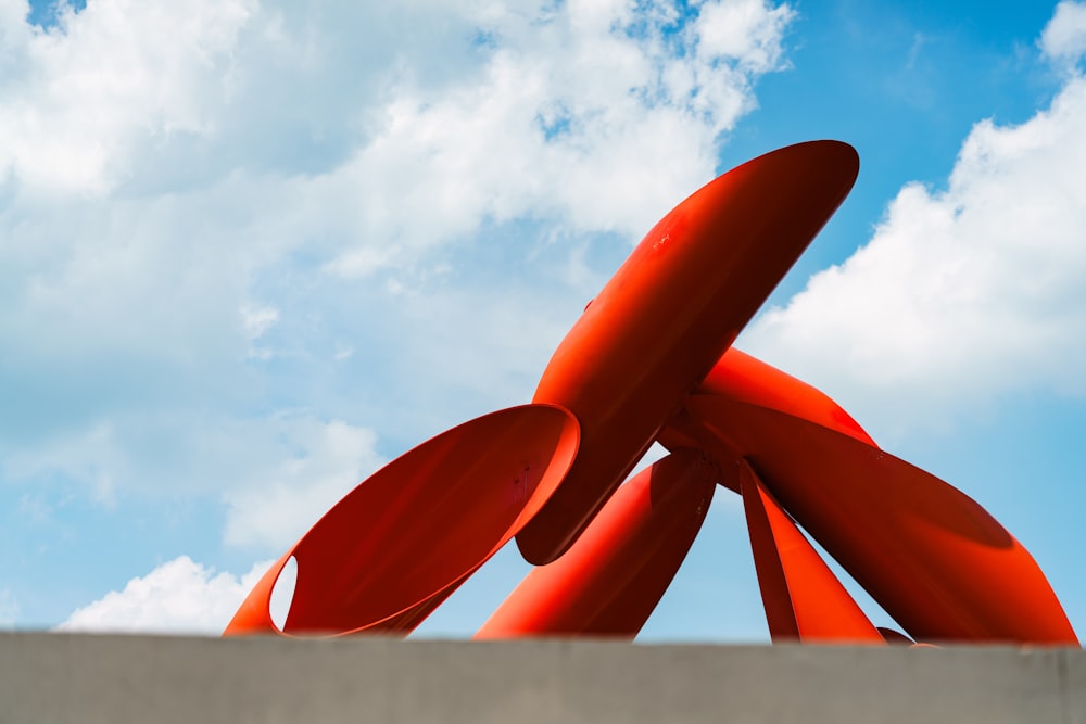 a large orange sculpture sitting on top of a cement wall