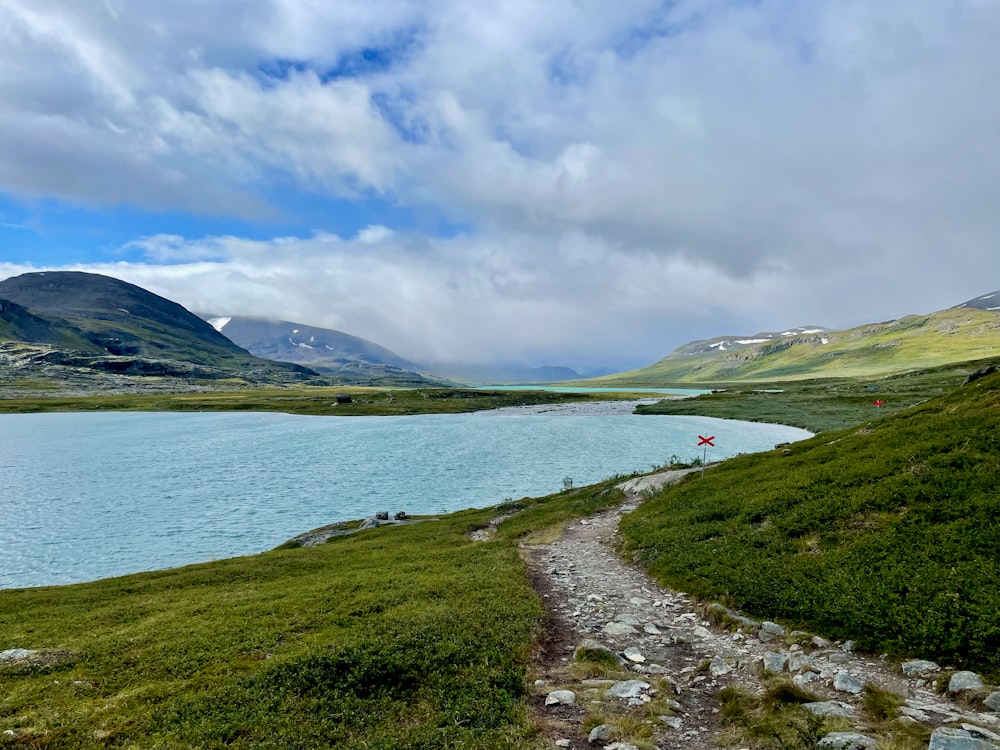 a path leading to a body of water with mountains in the background