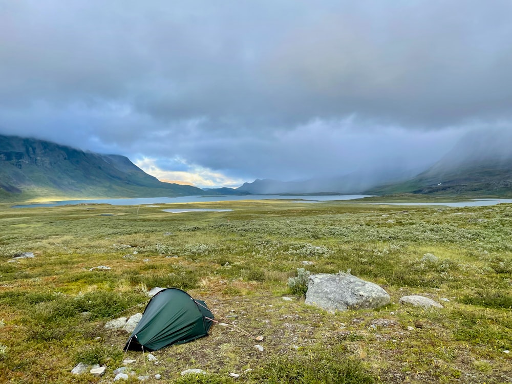 a tent pitched up in a field with mountains in the background