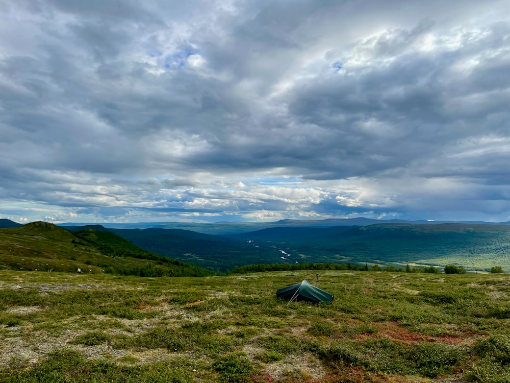 a tent pitched up on top of a grass covered hill