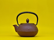 a teapot with a wooden handle on a yellow background